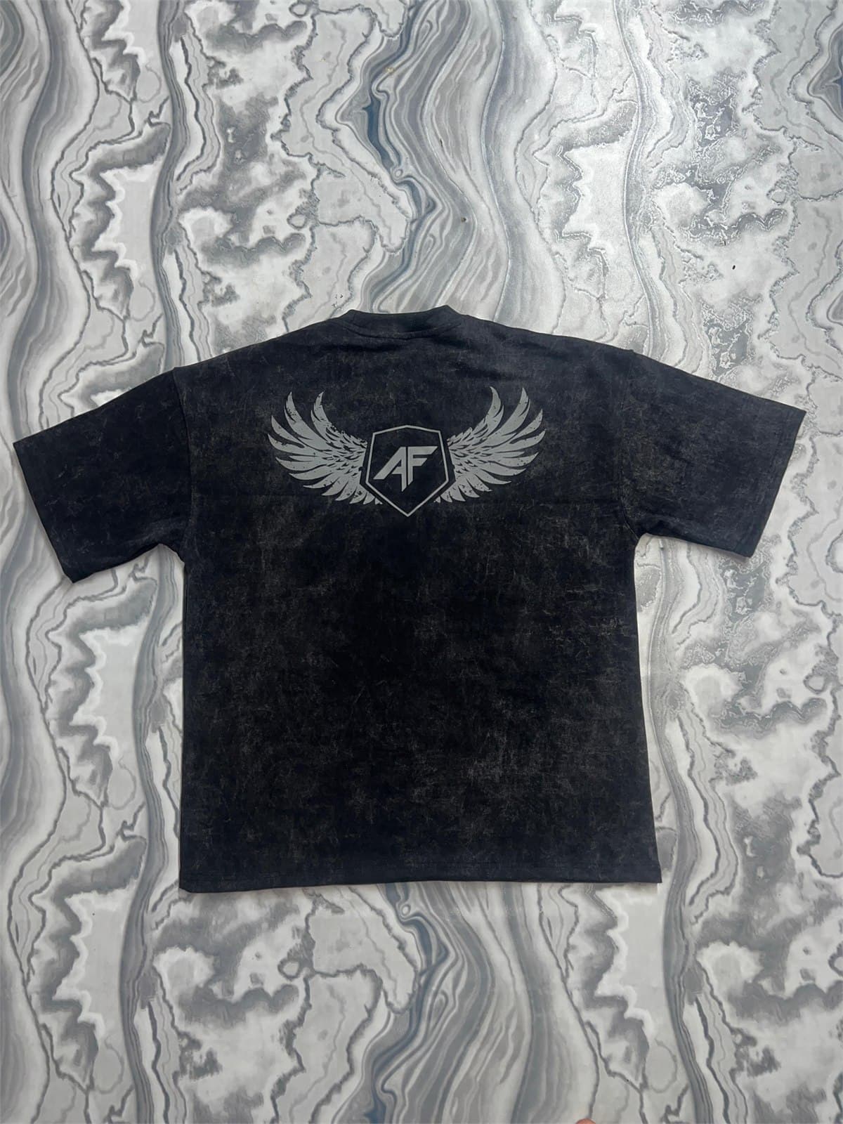 Authority Oversized Acid-Wash Tee — winged crest at back, on marble